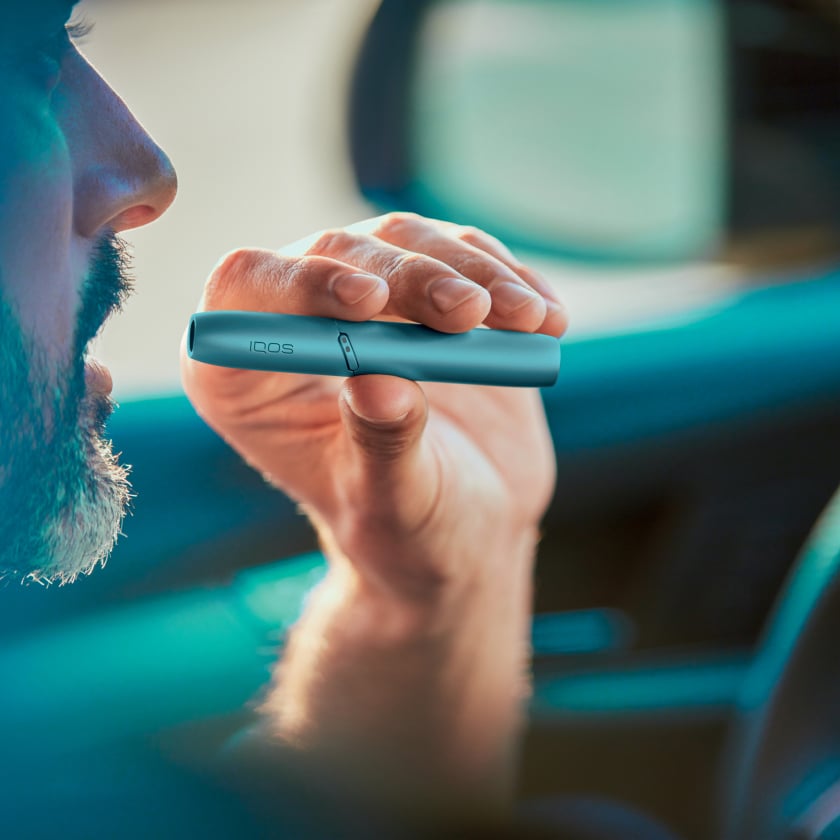 Hombre sosteniendo una pieza de calentamiento de IQOS Originals Duo turquesa.
