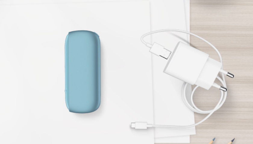 Cargador portátil de IQOS Originals DUO turquesa al lado de su cable cargador