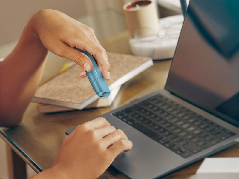 Manos escrbiendo en un laptop mientras sostiene un IQOS Originls One.