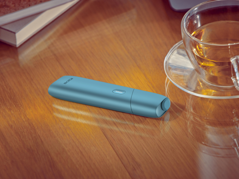 IQOS Originals One encima de una mesa al lado de una tasa de te.