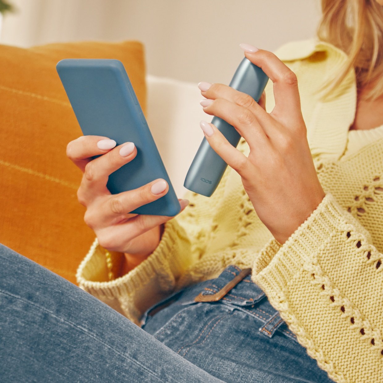 Mujer con celular y un IQOS Originls One descargando IQOS APP
