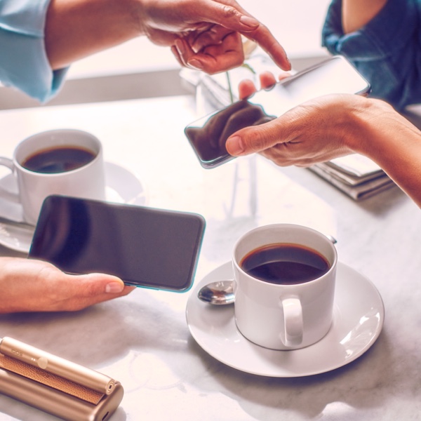 Dos personas con celulares tomando café