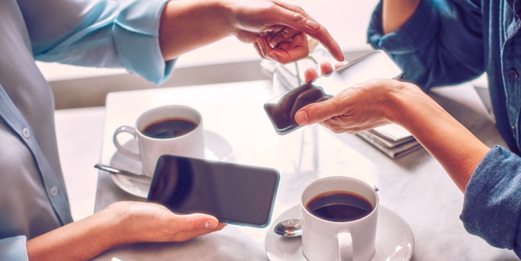 Dos personas con celulares tomando café