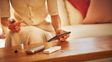 Woman with a IQOS holder in her hand and other accessories on a table