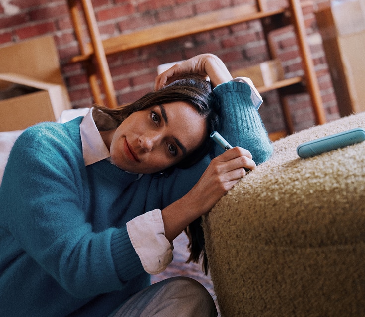 Mujer sosteniendo un dispositivo IQOS ILUMA i color Azul Brisa en su mano.
